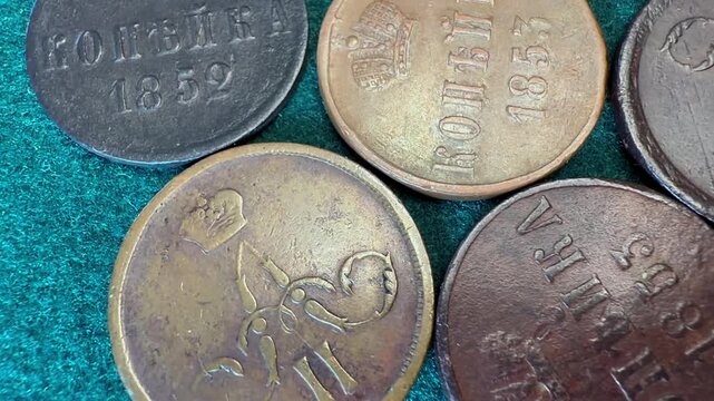 Close-up of old worn Russian Empire 1 kopeck coins 1849-1867 Nicholas I - Alexander II on green fabric, showing age, metal texture, and antique currency details for history, collecting.