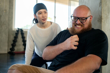 Fototapeta premium Personal trainer checking on an exhausted beginner who experienced shortness of breath and chest pain from fatigue after strenuous exercise