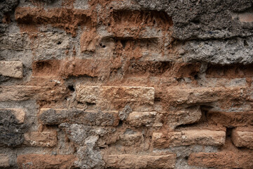 Fototapeta premium Ancient distressed red brick wall texture. Eroded rough masonry surface. Vintage weathered architectural background with copy space.