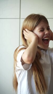 Close-up footage of a girl screaming while covering her ears and shaking her head in refusal, showing a strong sensory overload reaction and emotional distress expressed through both vocal 