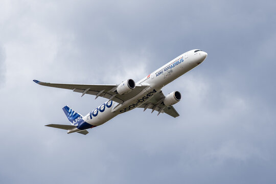 Berlin, Germany - June 14 2026. Airbus A350-1000 test aircraft passes overhead against dramatic cloudy sky revealing aerodynamic wing design twin engine configuration advanced aerospace engineering