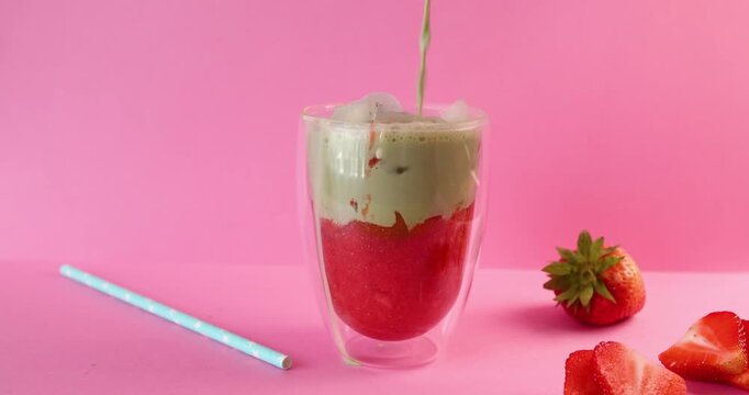 Pouring organic strawberry smoothie into empty glass for commercial food marketing. Healthy premium beverage option highlights vibrant red berry colors on uniform studio background. Professional