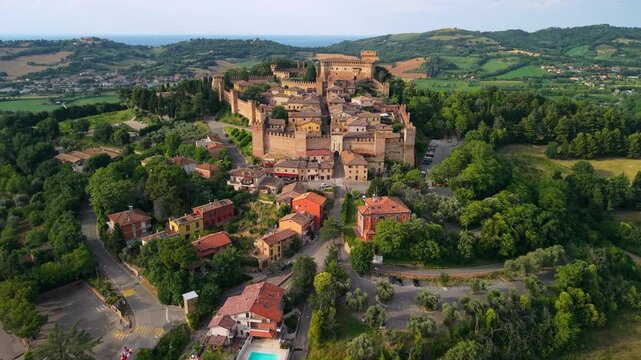 Gradara Marche Italy cinematic 4k drone sunset of medieval castle borgo symmetrical overflight. Aerial view of historic walled town towers and highway green fields beautiful villages of Italy b-roll
