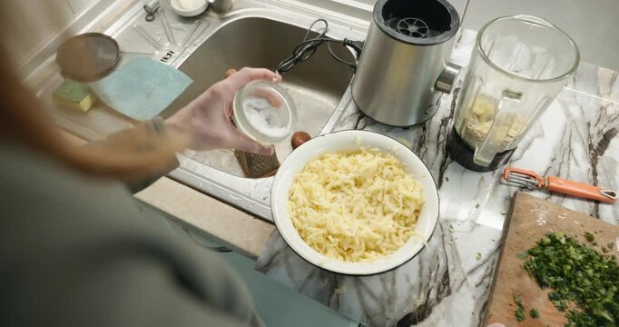 Caucasian man grate potato. Single male is cooking at kitchen at home. 4K 10-bit