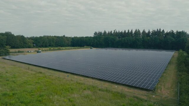 Vertical drone ascent revealing a large solar panel field surrounded by agricultural land. Aerial view highlighting renewable energy production integrated with modern farming landscapes.