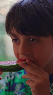 Young child enjoying juicy watermelon during quiet moment by window, wholesome family lifestyle scene highlighting healthy eating, comfort, wellbeing and childhood happiness
