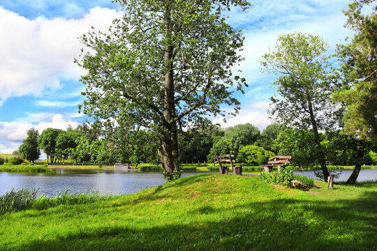 Outside seating area with wooden benches near to lake. Beautiful landscape with river, benches and green space. Europe. Picturesque landscape and leisure area for recreation and relaxation
