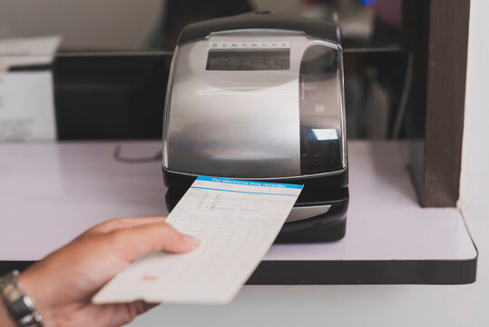 Punch card time clock machine processing attendance card in office setting, recording work hours and supporting workforce tracking and payroll accuracy.