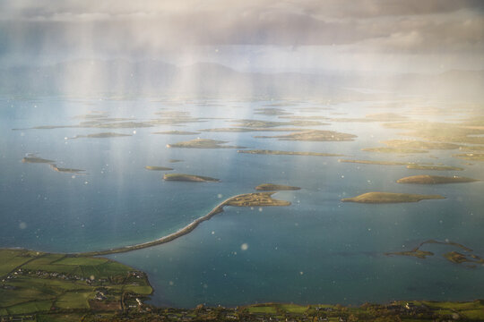 View of Clew Bay with its unique drumlin islands and green coastal fields under a dramatic sky with sunbeams Ireland.