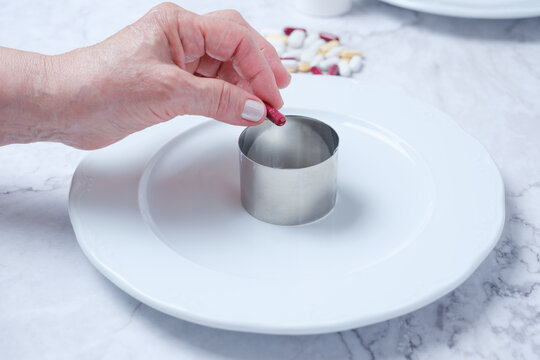 Hand placing capsule into metal ring on plate