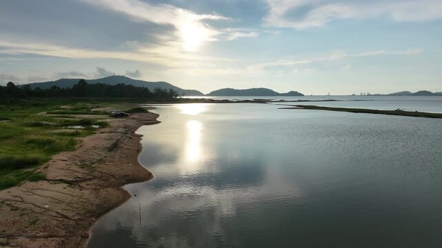 Aerial drone footage of a calm lake reflecting clouds and mountains at sunset light. Ideal for nature, travel, environment, wetland, and cinematic landscape projects.