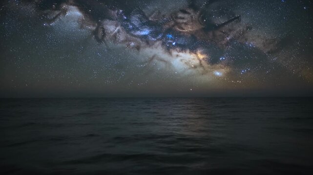 Nightfall revealing seascape showing Milky Way arching over open ocean, faint reflection
