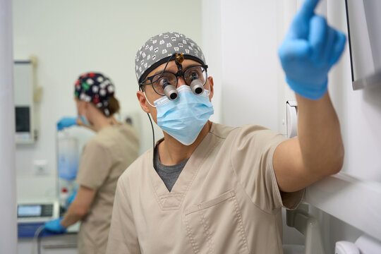 Dental professional wearing surgical loupes observing screen