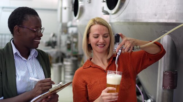 Brewery workers checking beer quality by pouring a draft
