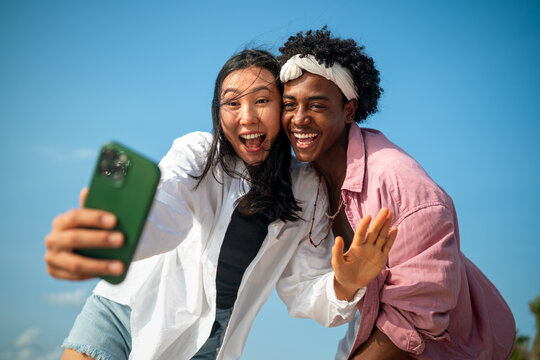 Diverse couple connected, embracing technology and social media while enjoying moments at the beach