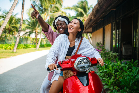 Young carefree tourists enjoying freedom and sunshine on a moped during a dream tropical vacation