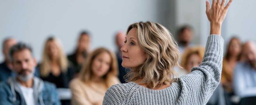 In a professional classroom, a mature student raises their hand, actively engaging in adult education.