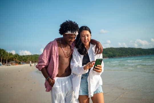 Trendy digital creator couple taking selfie by the beach, sharing travel content for social media