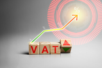 Wooden blocks spelling VAT with an upward pointing arrow, symbolizing value added tax increase,...