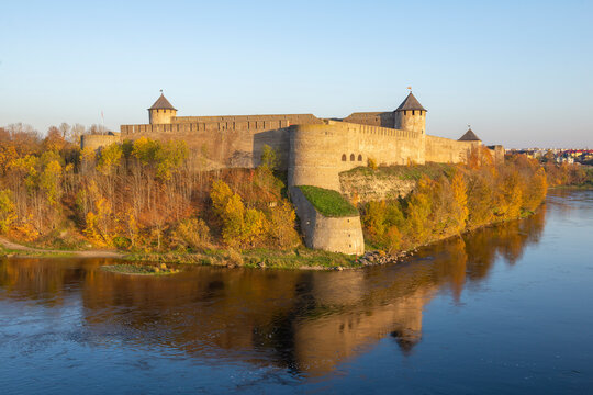 The ancient Ivangorod Fortress on a sunny October evening. View from the Narva River. Leningrad Region, Russia