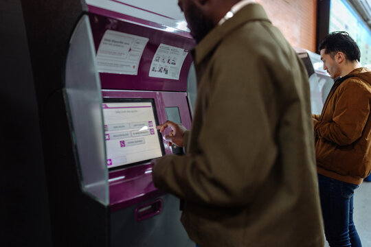 Man using subway ticketing machine purchasing travel tickets