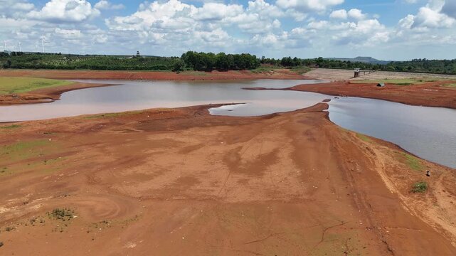 Drone footage captured above a river in Gia Lai Province, Vietnam, during the dry season. Filmed from a different aerial perspective, the aerial view shows exposed alluvial sediment, lush green vegeta