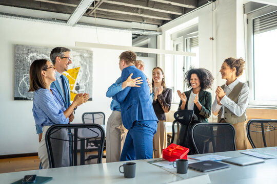 Business colleagues celebrating success with applause, hugging, and surprise gift