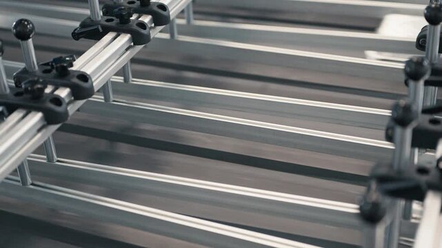 Aluminum foil containers sliding along automated conveyor system. High speed production process in modern packaging facility. Industrial manufacturing technology operating indoors.