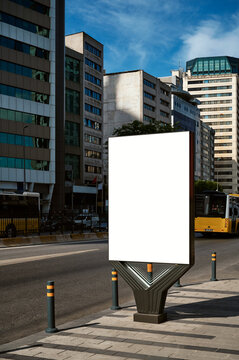 A large information display for outdoor advertising is installed on the street near the road.