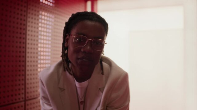 Portrait of young African American man wearing glasses and white suit gesturing towards camera. Clip perfect for corporate communication, diversity marketing, or creative agency campaigns