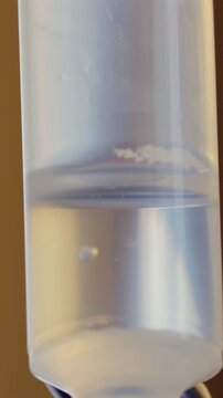Medical infusion droplets falling through drip chamber during treatment session, macro healthcare detail highlighting therapy administration, precision, monitoring and patient care