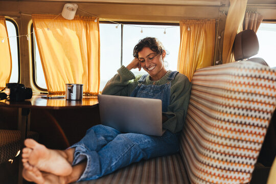 Easy evening work: Woman relaxes with her laptop inside a camper van
