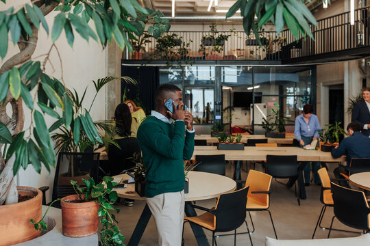Black entrepreneur talking on smartphone in modern green office
