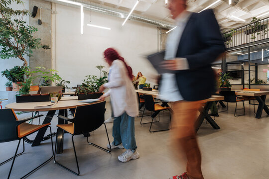Coworkers moving in a modern biophilic office