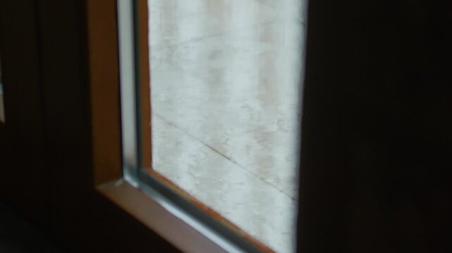 Rain balcony floor glass door, static tripod shot. Raindrops falling on wet terrace ground seen from interior perspective through window glass pane.
