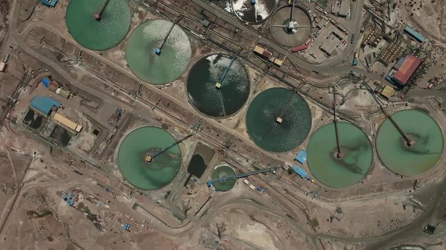 Aerial top-down footage capturing massive circular tailings thickeners operating within a copper mining complex in Chile. The industrial system supports solid-liquid separation and water recovery, con