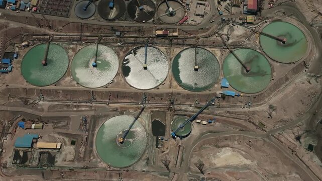 Forward-moving drone footage flying above a series of massive tailings thickeners at a copper mining operation in Chile. The clip highlights industrial-scale water recovery infrastructure, mineral pro