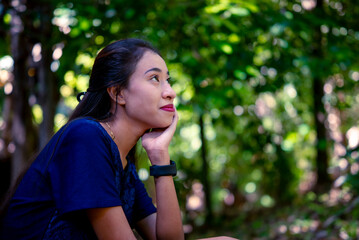Fototapeta premium A young woman rests thoughtfully in a green forest.