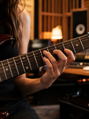 Obraz premium A musician's hand pressing the strings of an electric guitar in a recording studio. Passion for music and creativity.