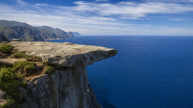 height. Flat rock at cliff edge overlooking deep blue sea. travel magazines, destination branding, designed for outdoor magazines and nature guides, used by software engineers.