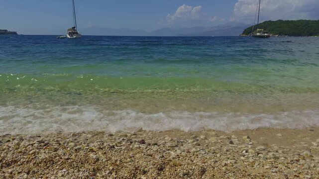 Sea Wave Crashing On Pebble Beach. Shore With Sailing Yachts Floating In Turquoise Water