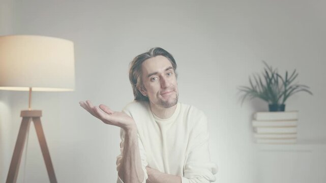 Young man shrugging with open palms indoors, confusion and doubt concept