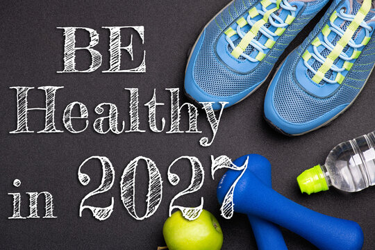 New year 2027 resolutions healthy lifestyle and sport. Be healthy in 2027. Motivation sport goals 2027 with sport equipment shoes, dumbbells, fruit and water bottle on black background