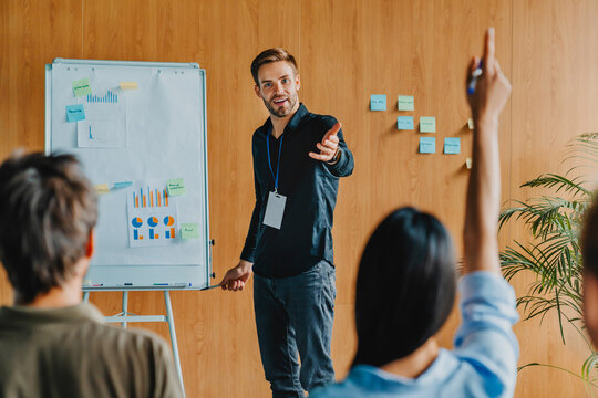 Businessman giving presentation and discussing project with group of people during corporate training, business seminar concept, teamwork collaboration, professional communication and office meeting