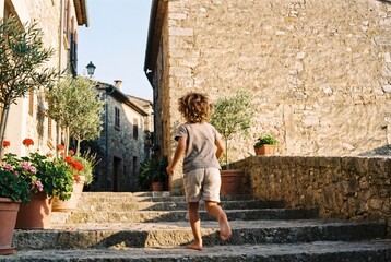 Fototapeta premium Carefree little boy running up the stone steps of a traditional village street.