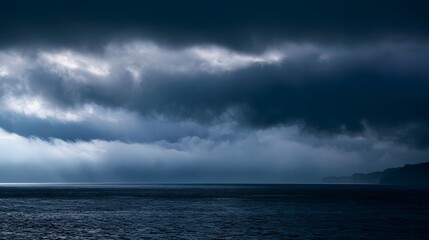 Fototapeta premium Glistening storm clouds hover over the ocean creating a tranquil and dramatic seascape with rolling mist and striking highlights