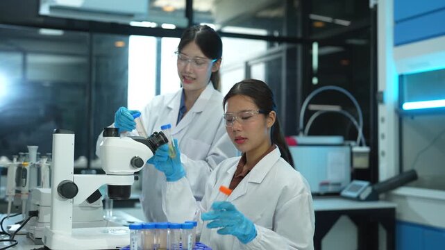 Team of biochemical research scientists working with a microscope for vaccine development in pharmaceutical research labeling.