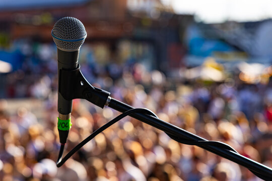 rofessional vocal microphone close up on live concert stage with blurred crowd background