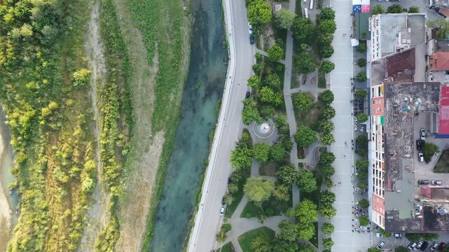 Straight-down aerial drone footage at 90&deg; nadir angle, flying forward above the Osum River in Berat, Albania, an abstract bird's-eye perspective revealing the river's winding form.
