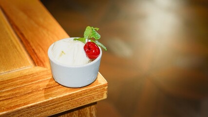 Vanilla ice cream cup topped with cherry and mint leaf © Liada